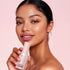 Woman holding a ETUDE nymph aura volumer against a pink background